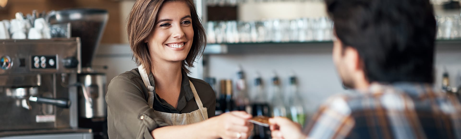 Shot of a cheerful female bartender receiving a card as payment from a customer inside of a restaurant