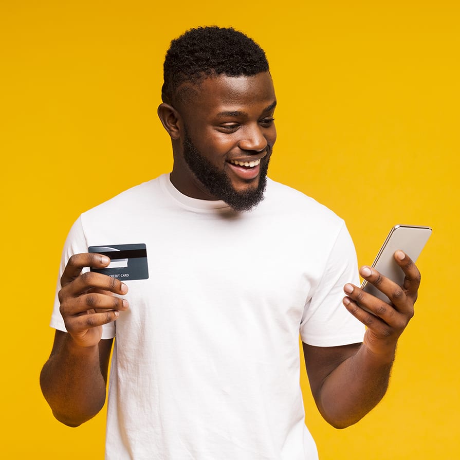 happy guy looking at phone and holding debit card in other hand