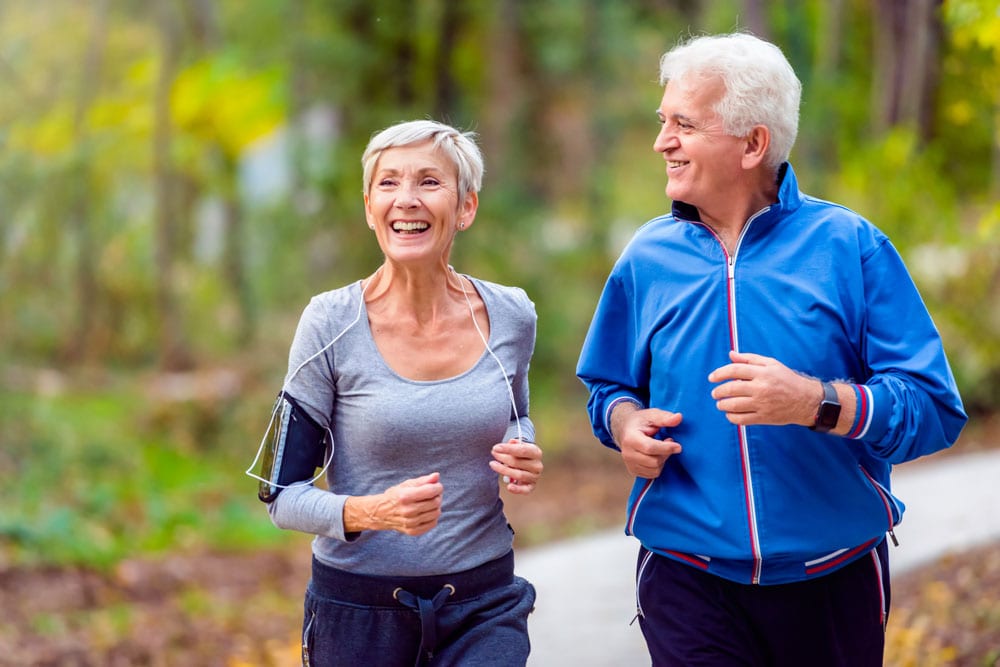 happy older couple taking jog down trail