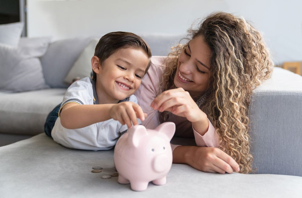 mom and daughter adding savings to piggy bank