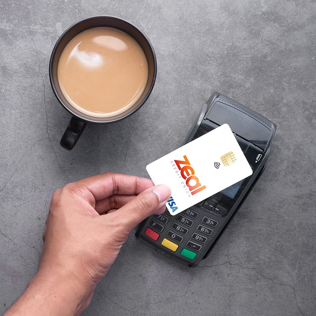 Zeal Tap to Pay. Hand holding Zeal credit card over wireless payment system.